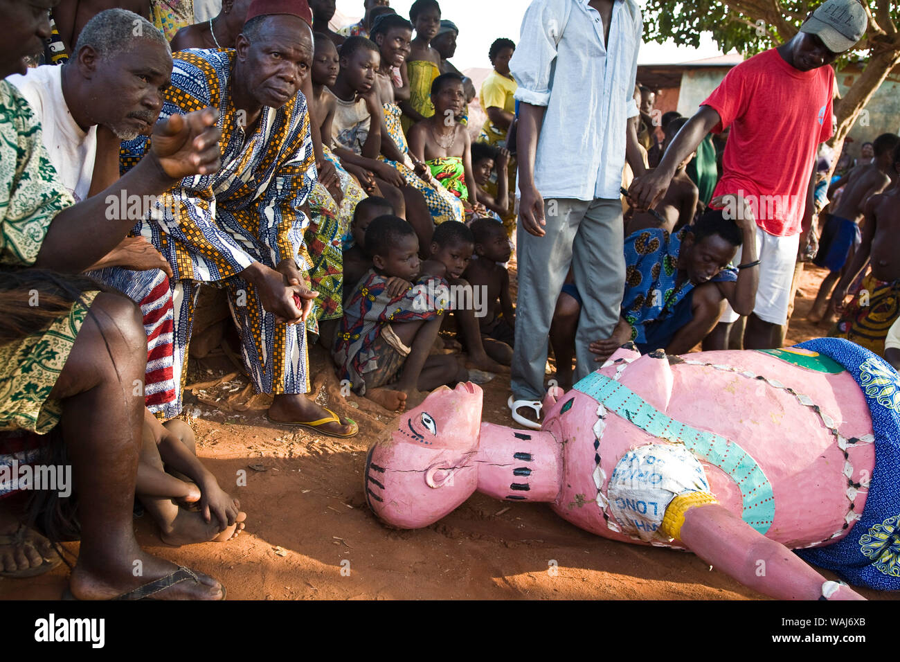 Africa occidentale Benin. Maschera Gelede ballerino scende drasticamente a terra come uomini, bambini e anziani del villaggio orologio. Foto Stock