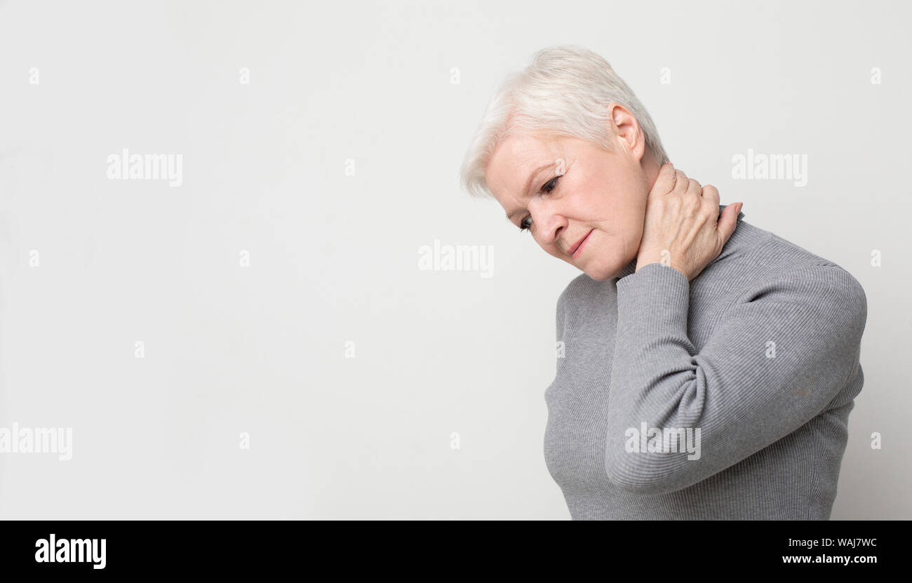 Senior donna che soffre di dolori al collo e la sensazione di esaurimento Foto Stock