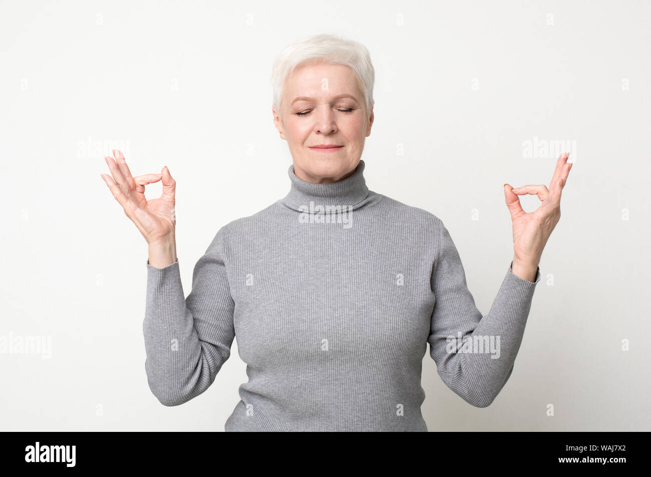 Serena donna senior meditando con gli occhi chiusi Foto Stock