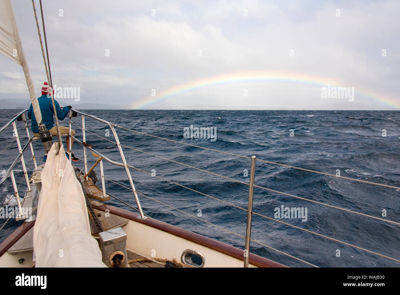 Australia e Tasmania, Maria Island. L'uomo godendo arcobaleno nel Mare di Tasman dalla prua della nave. (MR) Foto Stock
