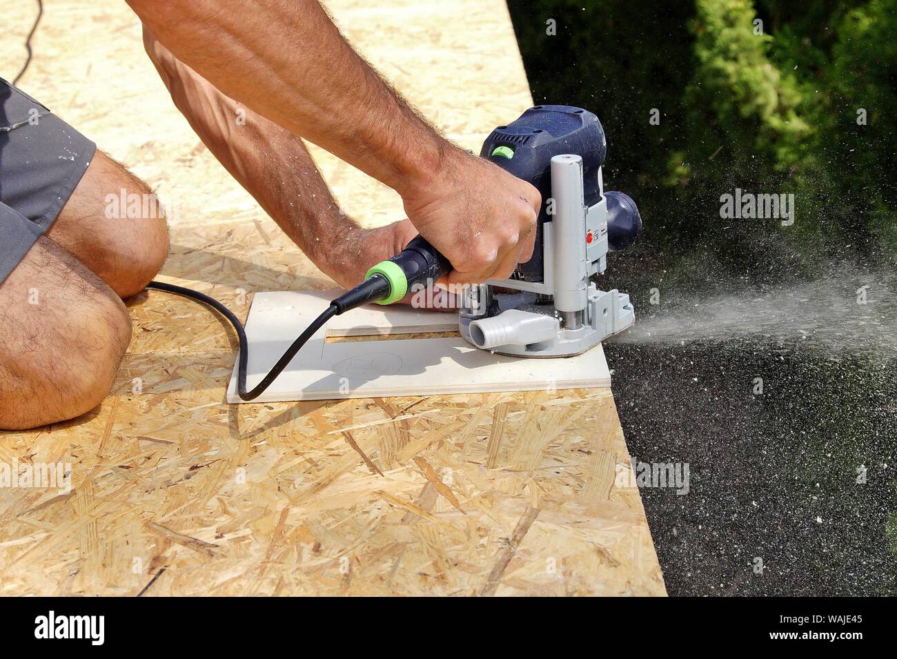 Preparazione con la fresa per staffe di ferro di una gronda del tetto sul  sito in costruzione. Mano maschio di carpenter detiene un attrezzo.  grondaie acqua Foto stock - Alamy