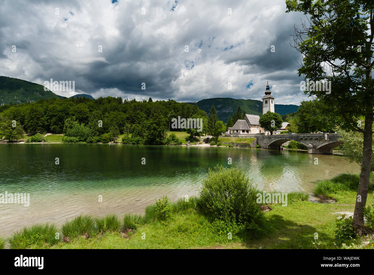 Chiesa di San Giovanni Battista e il ponte di pietra sul lago di Bohinj, Slovenia. Foto Stock