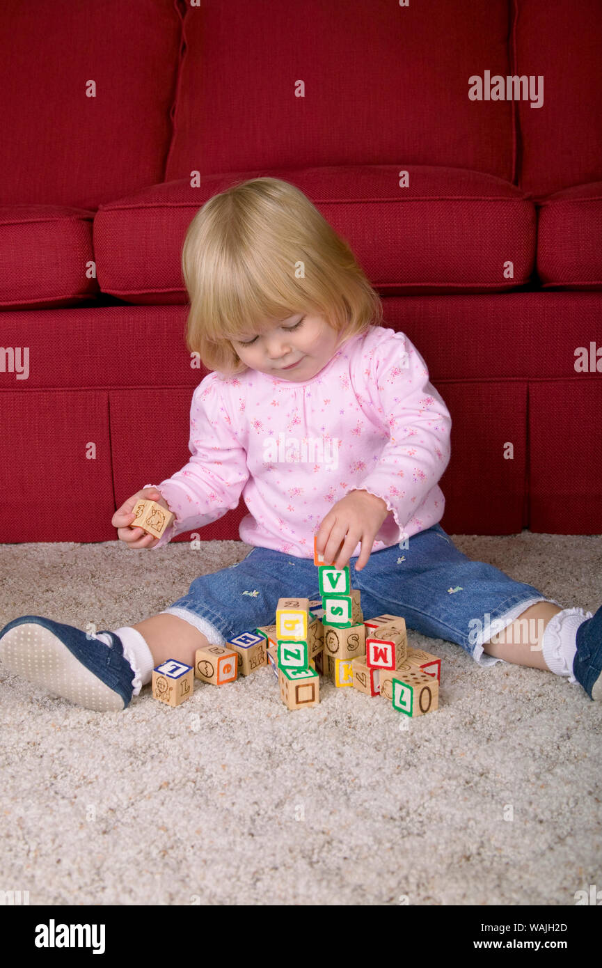 22 mesi ragazza toddler mostra orgoglio di essere in grado di costruire una pila di blocchi. (MR) Foto Stock