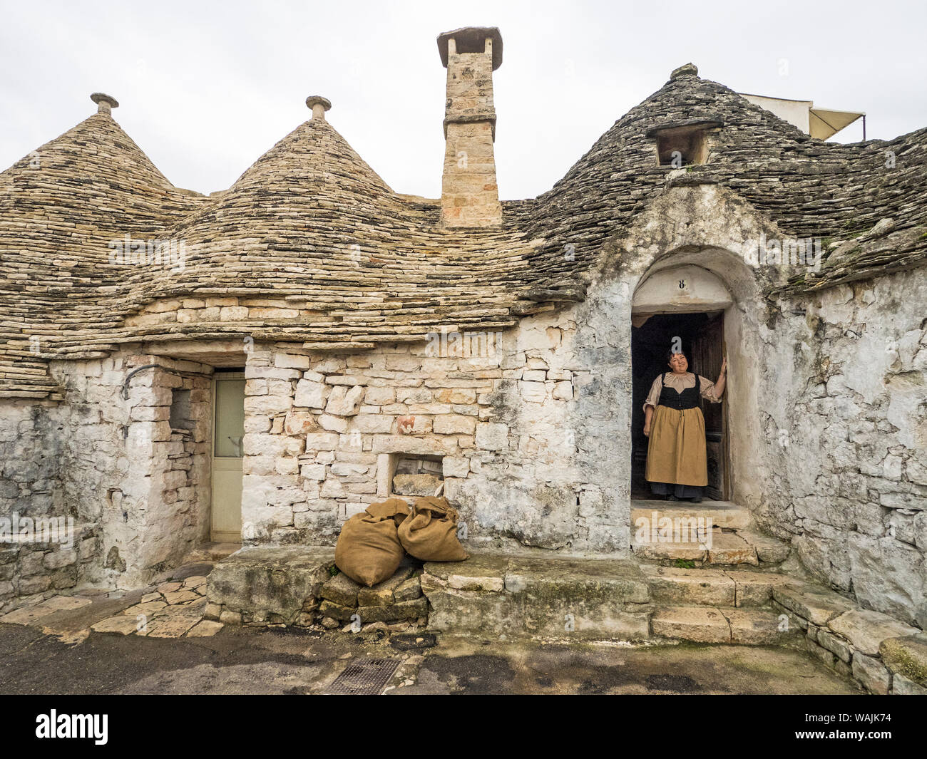 L'Italia, Alberobello. Donna in abiti tradizionali in porta. Foto Stock