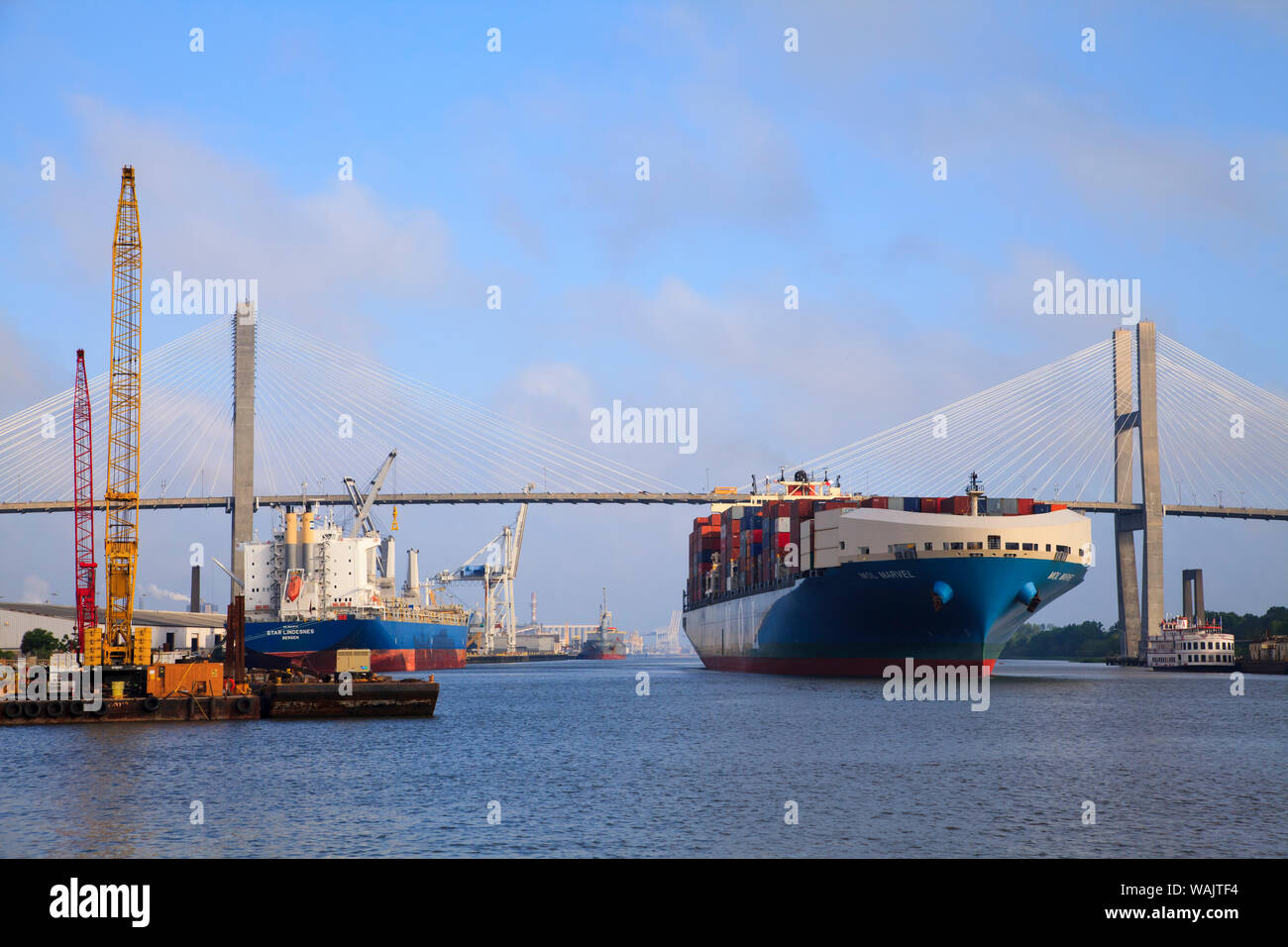 Stati Uniti d'America, Savannah, Georgia. Costruzione lungo il Fiume Savannah vicino a cavo alloggiato a ponte con nave da carico lasciando port. Foto Stock