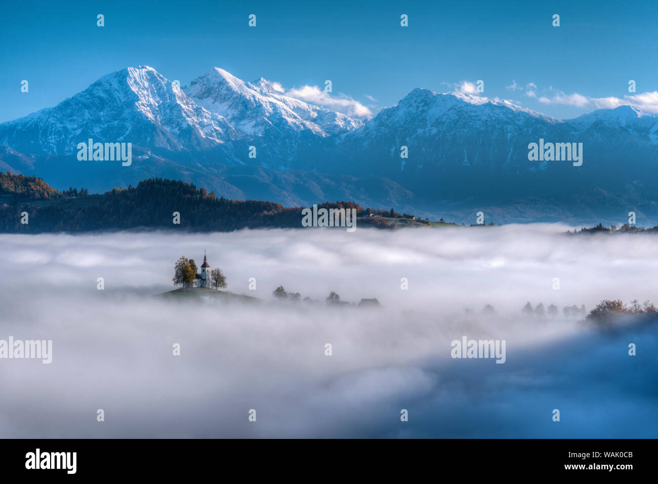 La Slovenia. Chiesa di Sveti Tomaz in Skofja Loka, prendendo in alto attraverso la nebbia di strato con le Alpi Giulie in background. Foto Stock