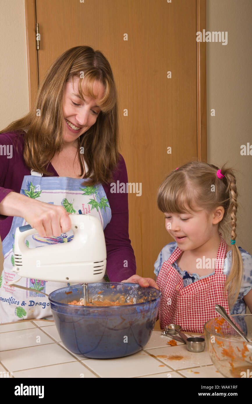 Guardare la ragazza madre mix torta di carote di pastella nel recipiente di miscelazione. (MR, PR) Foto Stock