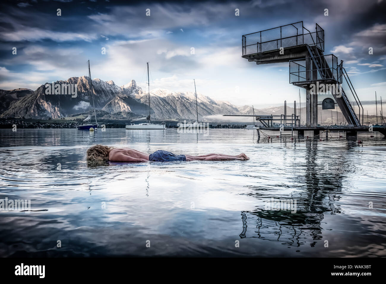 L'uomo fasciame / la posa a faccia in giù in acqua fredda con piattaforma subacquea riflettendo sulla superficie dell'acqua Foto Stock