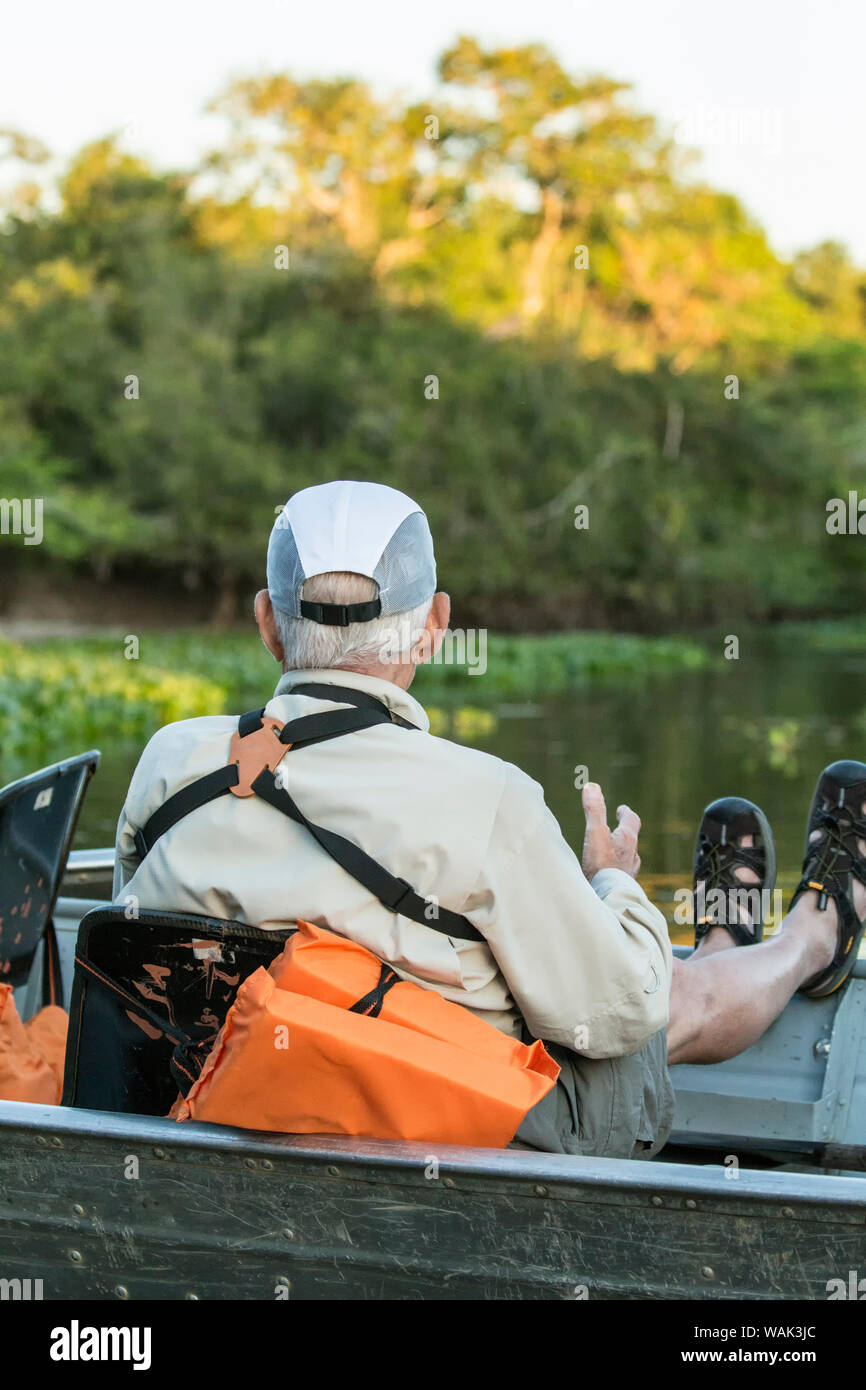 Pantanal, Mato Grosso, Brasile. Maschio di turisti in un tour in barca in attesa di una Jaguar per spostare su un fiume safari. (Solo uso editoriale) Foto Stock