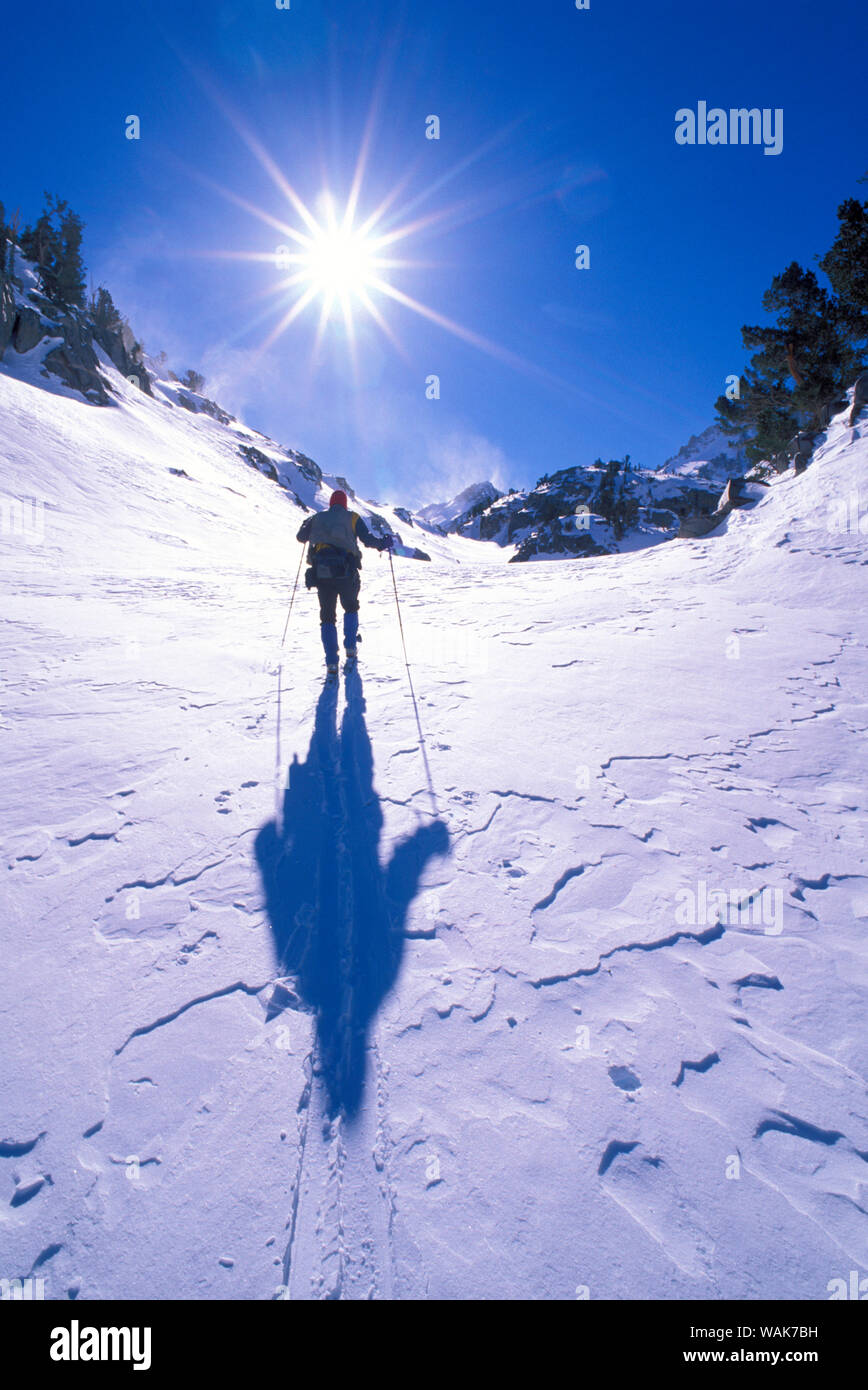 Backcountry rider crossing vento neve soffiata nei pressi dei laghi del tesoro, John Muir Wilderness, California (MR) Foto Stock
