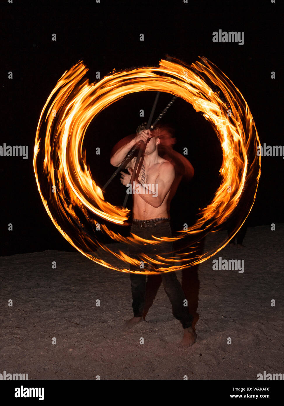 Fire performer fuoco oscillante su un bastone facendo un cerchio di fuoco Foto Stock