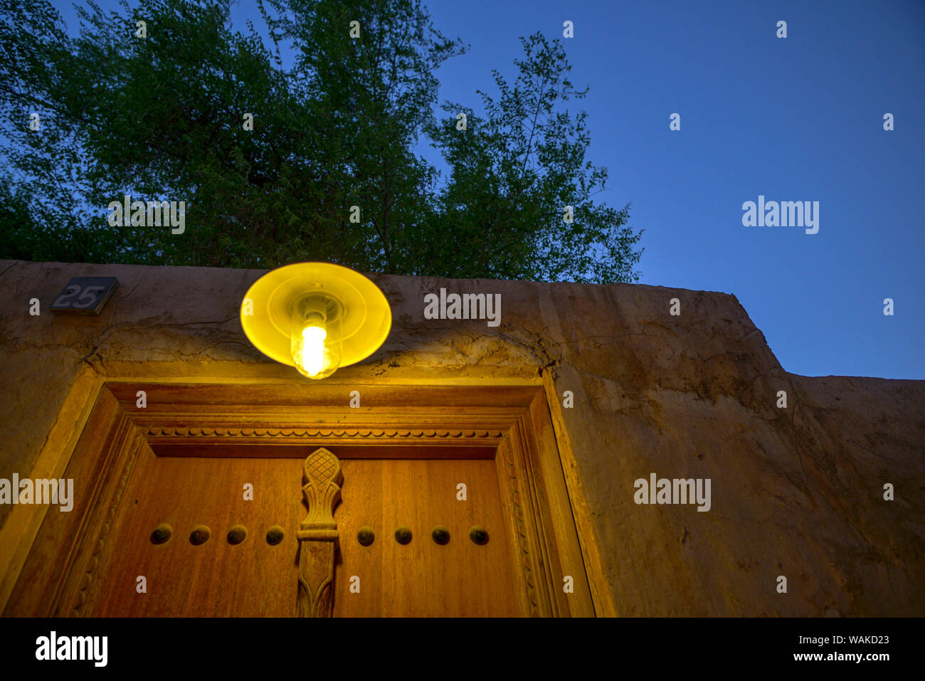 Vintage apparecchio di illuminazione sotto un albero e al di sopra di una porta, prese al tramonto nel Souq Wakrah, in Qatar Foto Stock