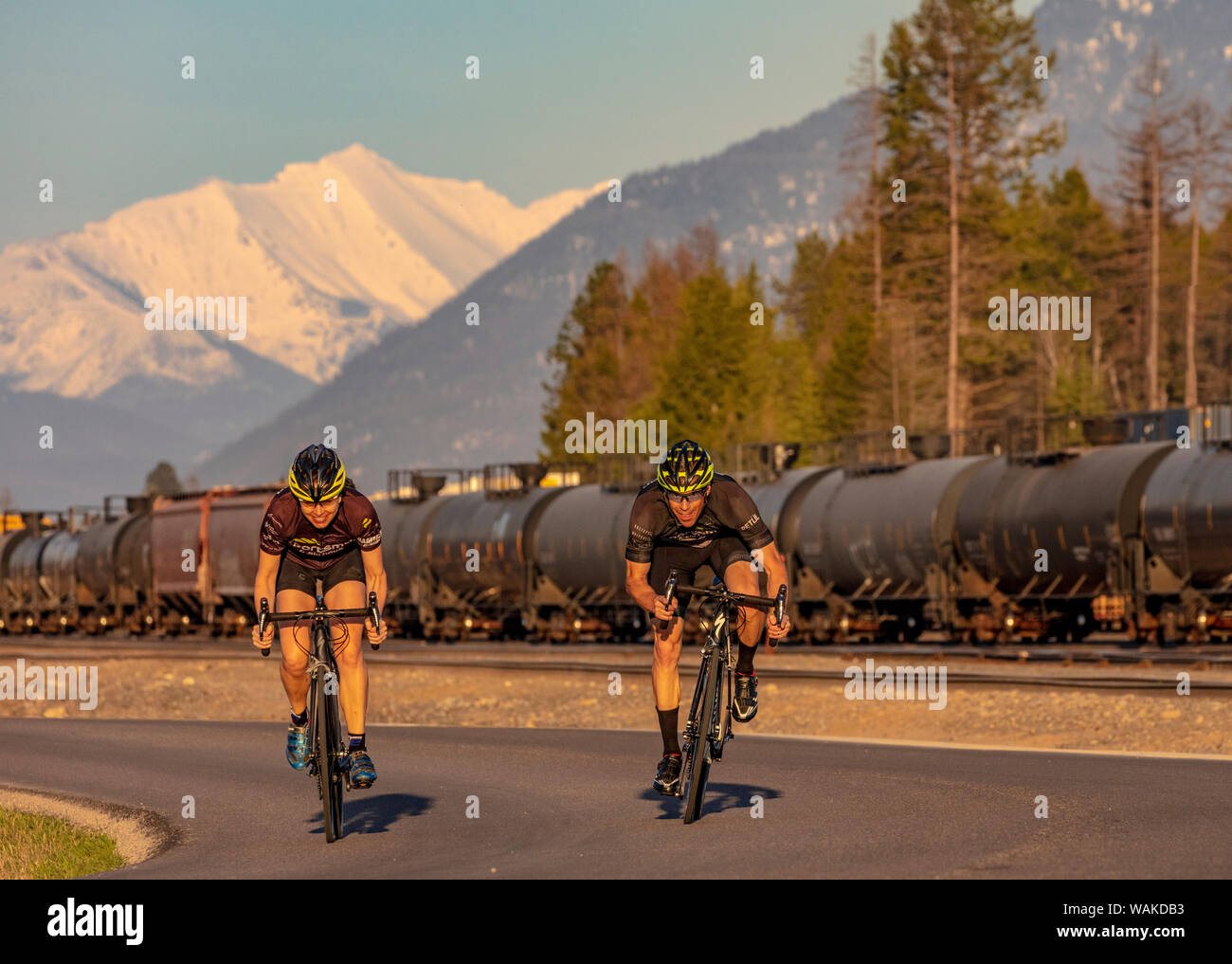Accoppiare il ciclismo su strada a Edgewood Road con grande montagna settentrionale e railyard in background in coregoni, Montana, USA (MR) Foto Stock