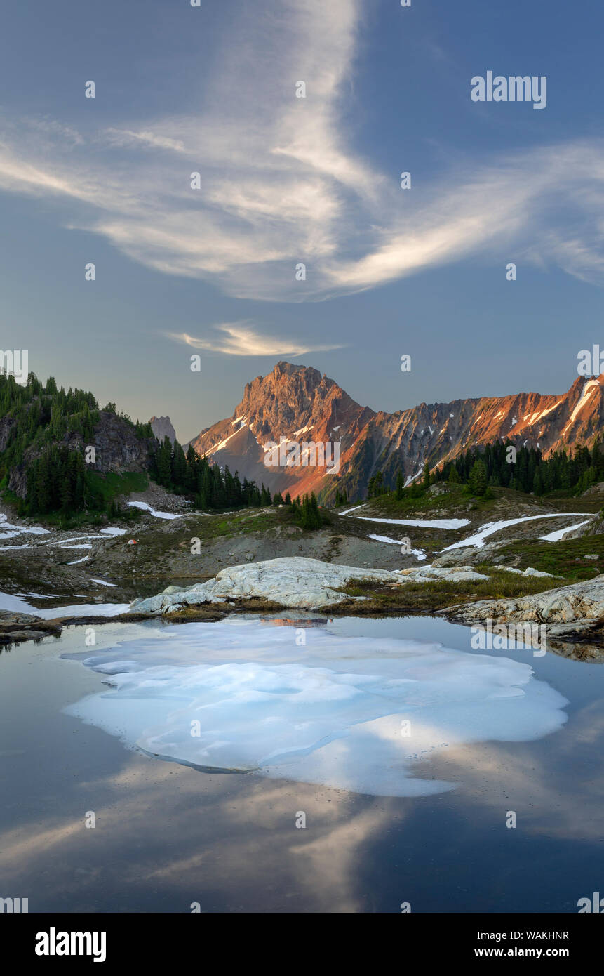 Parzialmente scongelato tarn, giallo Aster Butte bacino. Confine americano picco è nella distanza. Mount Baker deserto, North Cascades, nello Stato di Washington Foto Stock