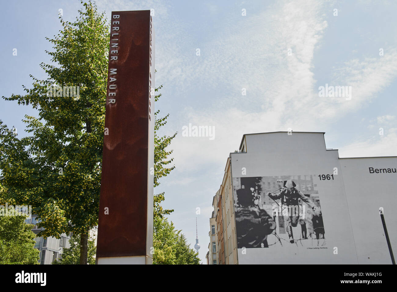 Berlino, Germania. Xiii Giugno, 2019. Un picchetto arrugginito sorge alto nel cielo blu. Con le iscrizioni "Berliner Mauer' e 'Bernauer Straße' serve come un monumento alla guerra fredda. La famosa immagine mostra il confine in fuga poliziotto Conrad Schumann. Questa immagine, denominata "prung in die Freiheit" è dipinto sul muro di casa a Brunnenstraße. Credito: Annette Riedl/dpa-Zentralbild/ZB/dpa/Alamy Live News Foto Stock