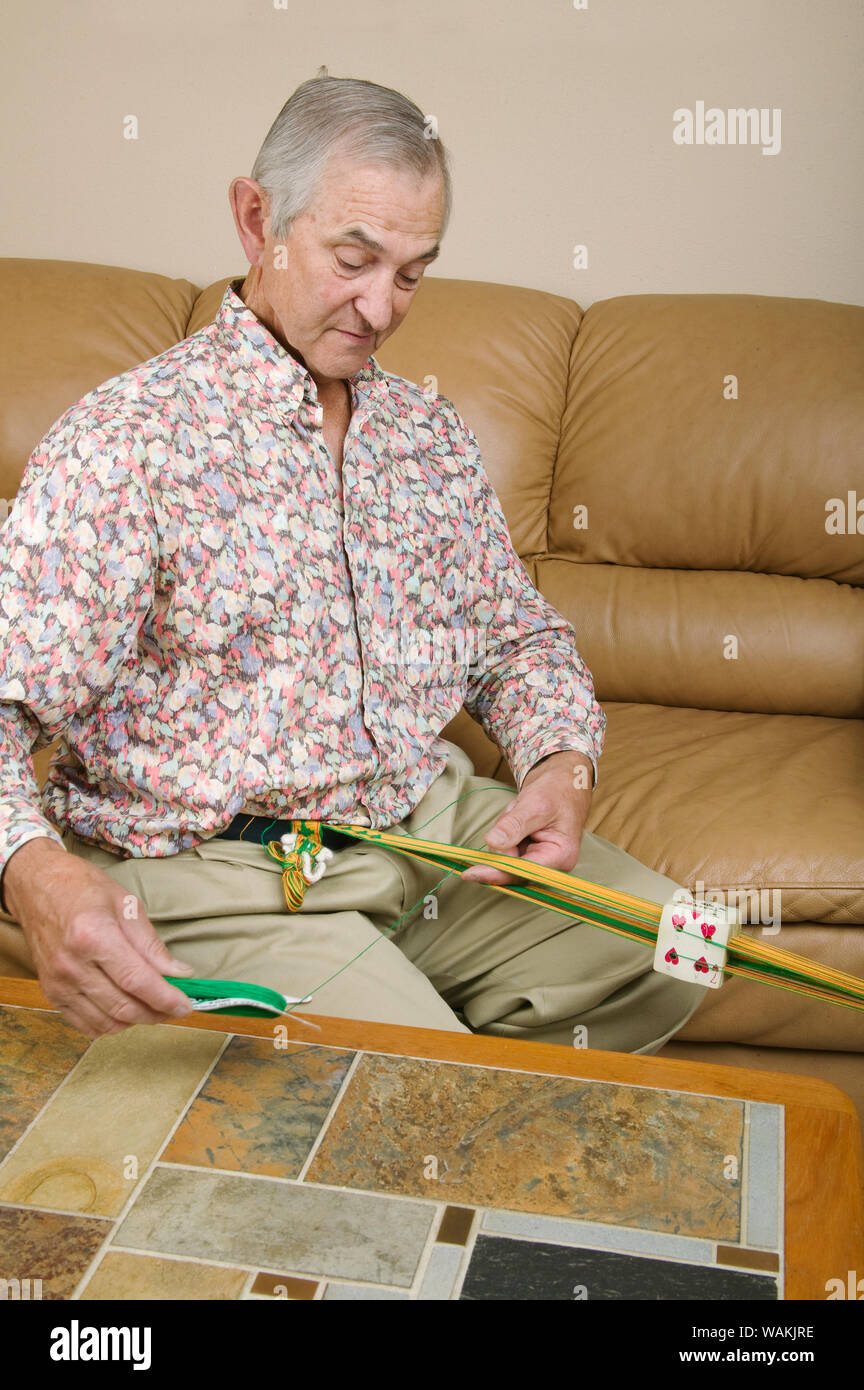 Uomo che fa la tessitura della scheda, rendendo una cinghia nella sua casa. (MR, PR) Foto Stock