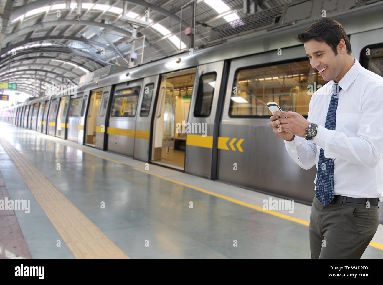 Messaggistica di testo per uomini d'affari sul telefono cellulare su una piattaforma metropolitana Foto Stock