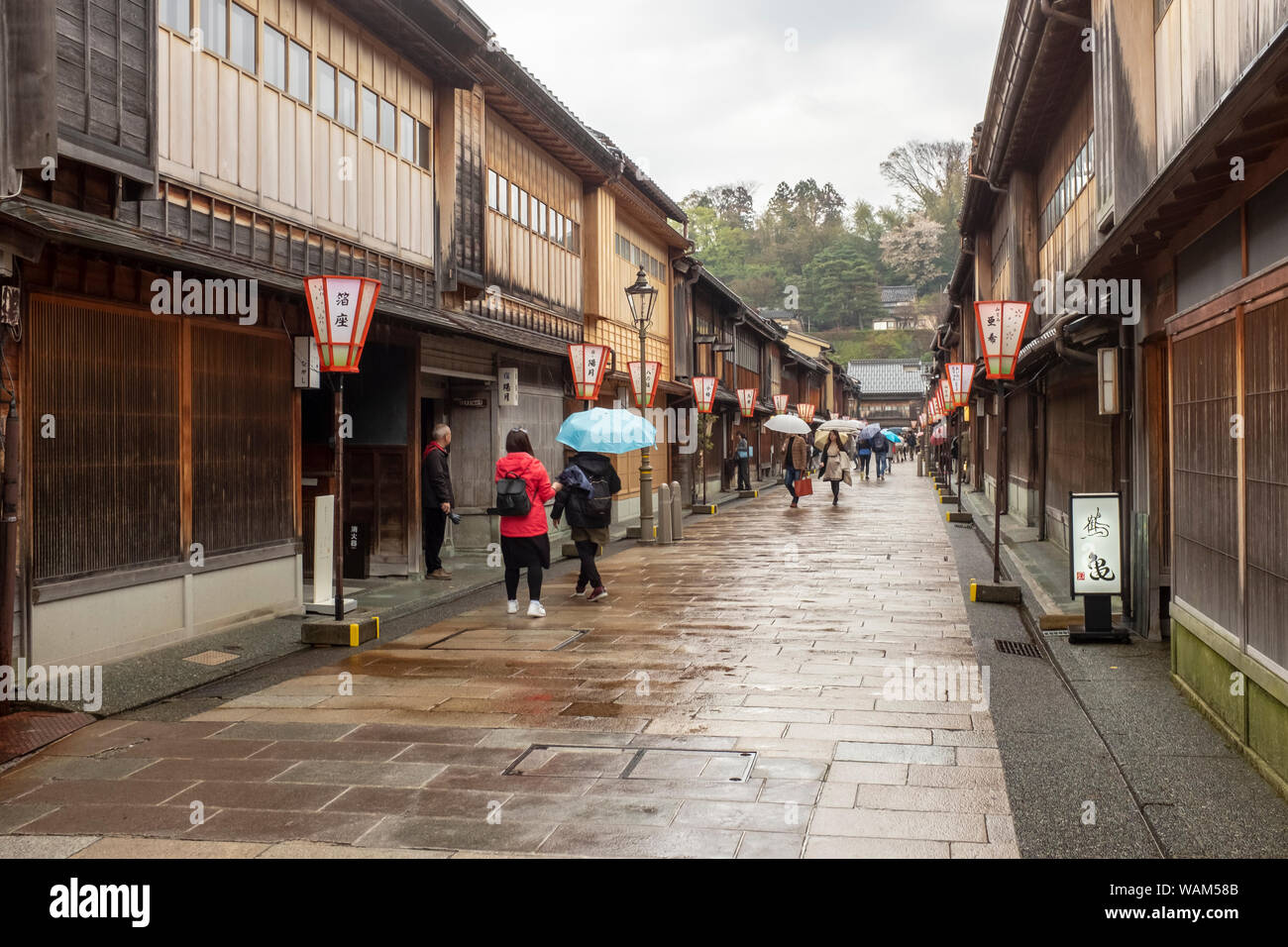 I turisti con ombrelloni a piedi verso il basso di una corsia di marcia foderato con architettura tradizionale nell'Higashi Chaya Geisha District, Kanazawa, Giappone Foto Stock