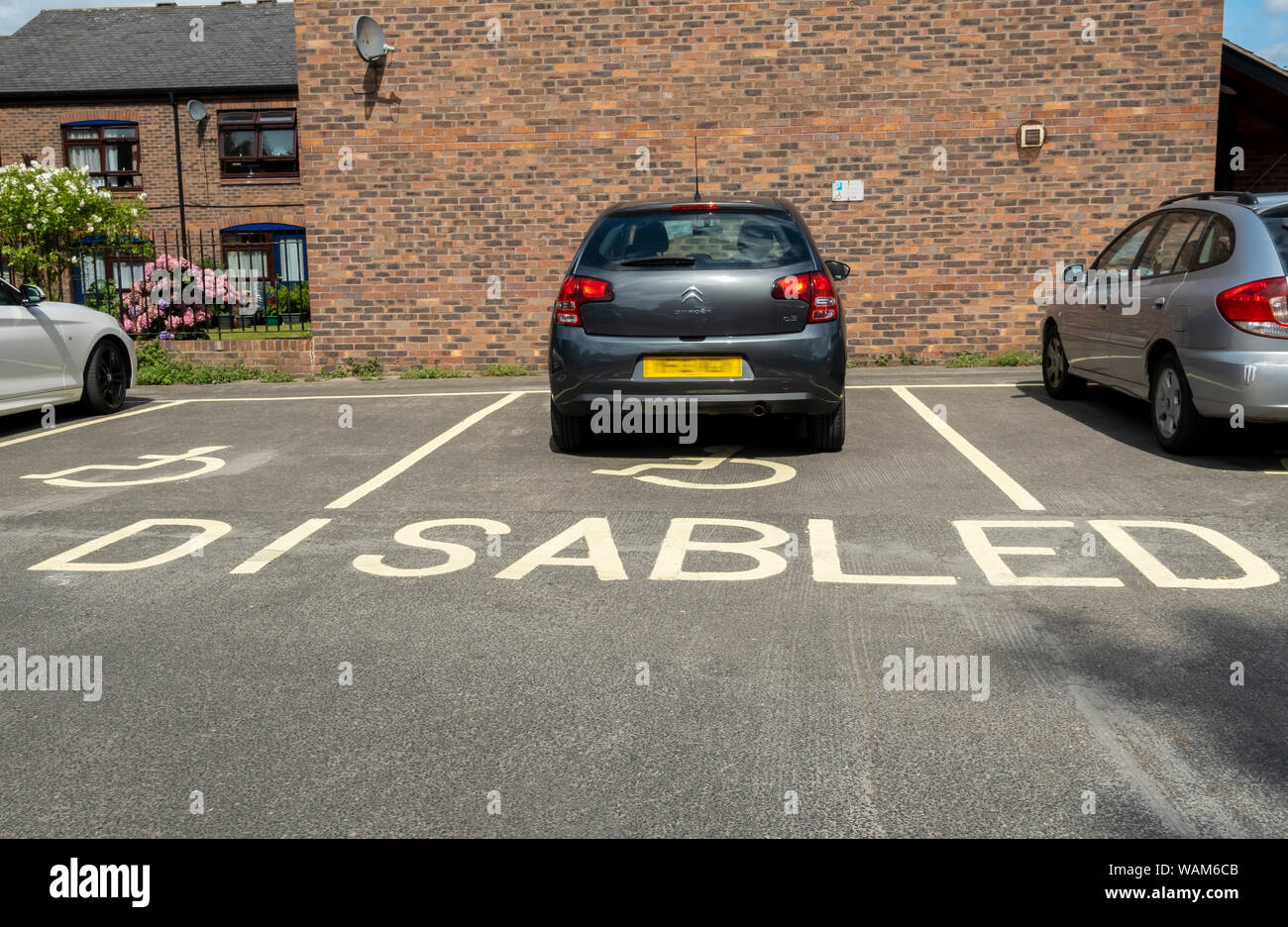 Auto auto parcheggiate in spazi riservati ai disabili spazio con sedia a rotelle simbolo Inghilterra Regno Unito GB Gran Bretagna Foto Stock