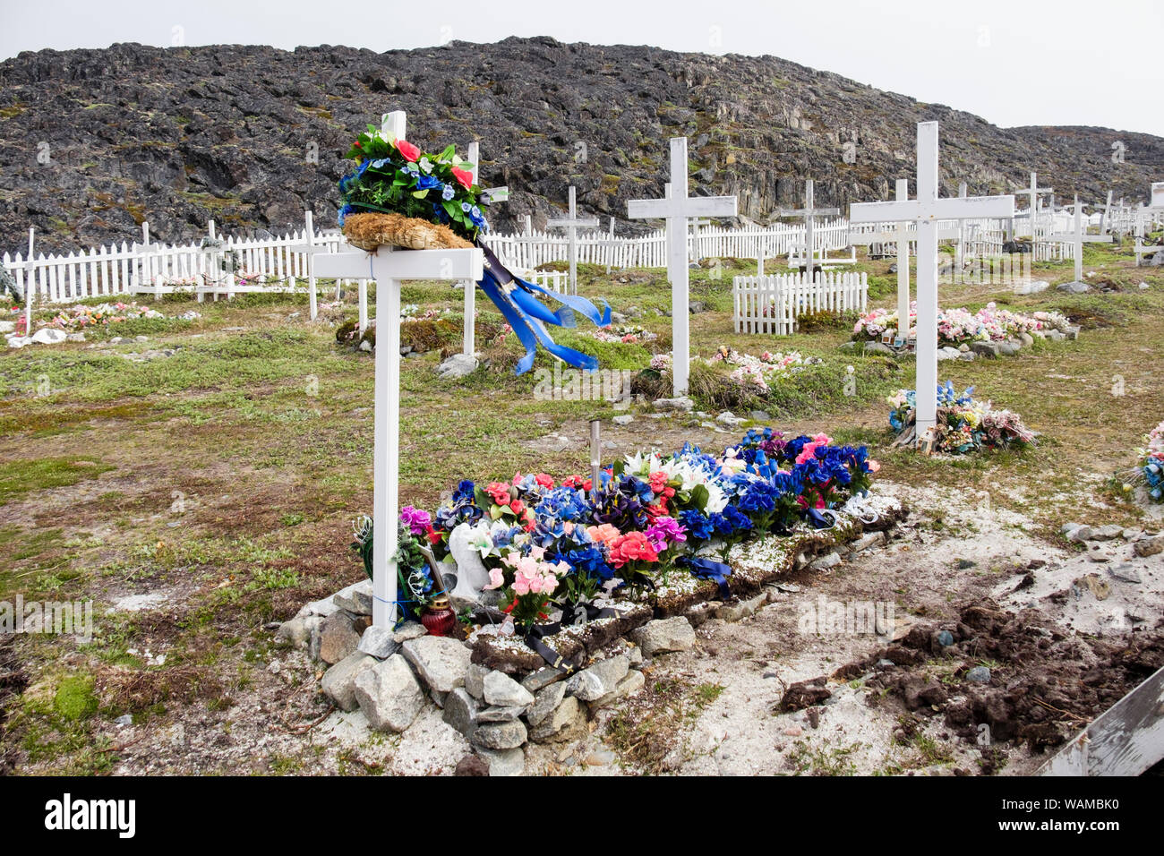 Plastica fiori artificiali e bianco croci di legno sulla tradizionale insediamento inuit tombe in un cimitero. Itilleq, Qeqqata, Groenlandia Foto Stock