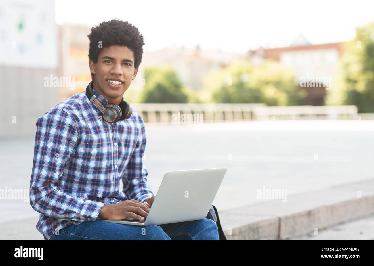 Giovane bella studente seduto con laptop contro cityscape Foto Stock