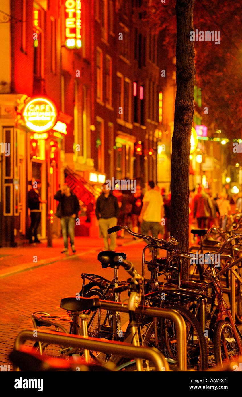 Le Biciclette parcheggiate e pedoni sulla banca Canale di Beagle notte strade del quartiere a luci rosse di Amsterdam Foto Stock