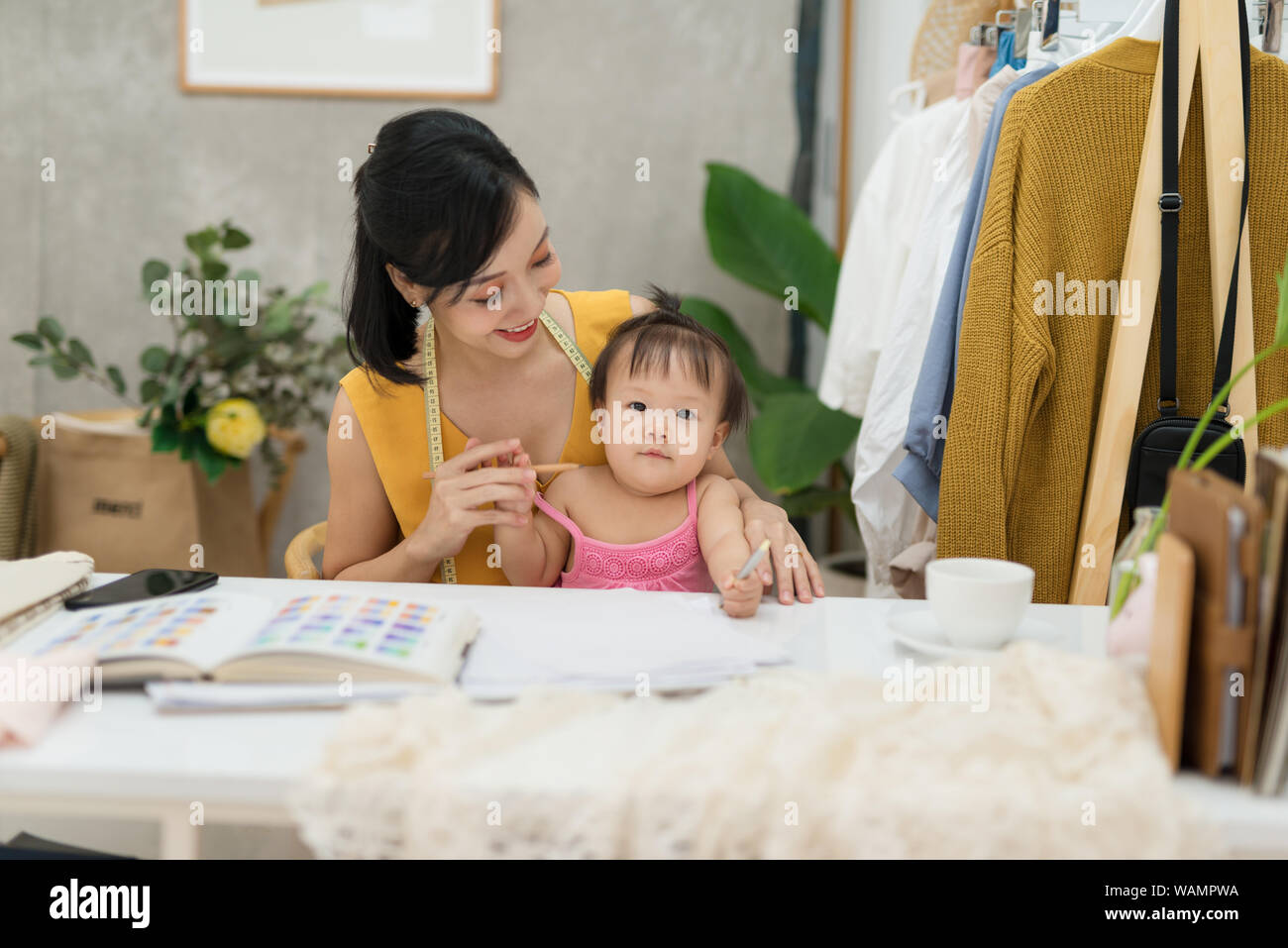 Giovane donna che lavorano con il Bambino sulle ginocchia Foto Stock