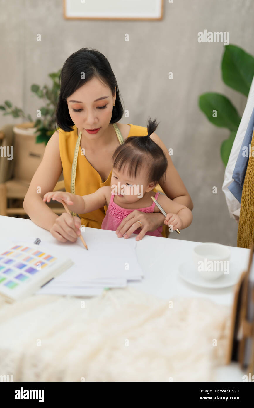 Giovane donna che lavorano con il Bambino sulle ginocchia Foto Stock