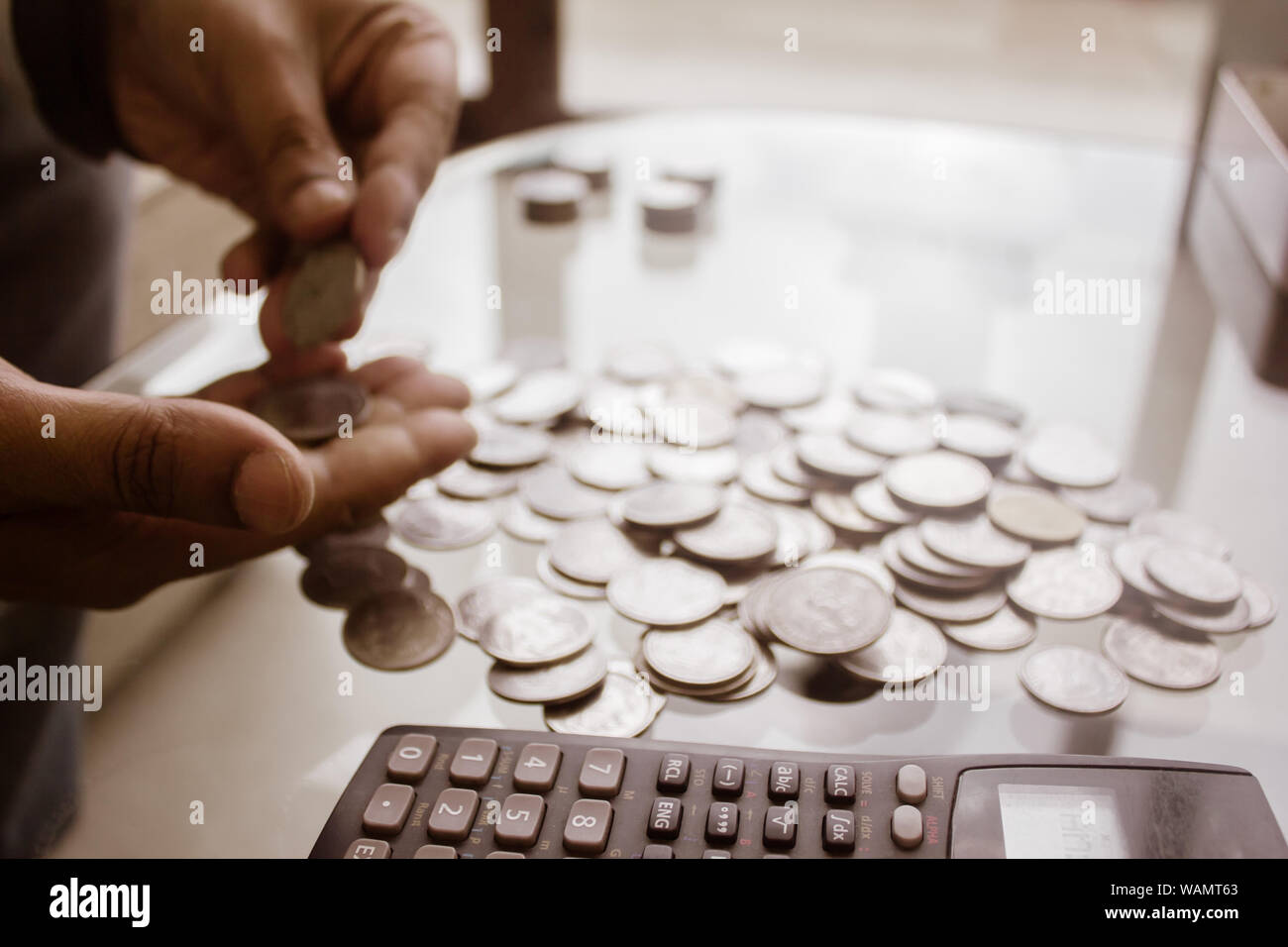 Immagine ritagliata di imprenditore contare monete utilizzando la calcolatrice a scrivania in ufficio. Commercianti lato contare monete. Finanza aziendale e risparmio Inves Foto Stock