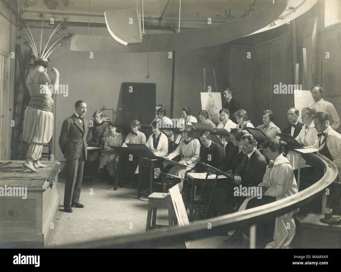 Scuola di Arte del 1920s. Interno da una classe di Edward Berggrens la pittura e la scuola di arte a Stoccolma. Gli studenti sono seduti in un mezzo cerchio e un modello che indossa tipico degli anni venti e abiti vestito è in piedi in posa per loro. Foto Stock