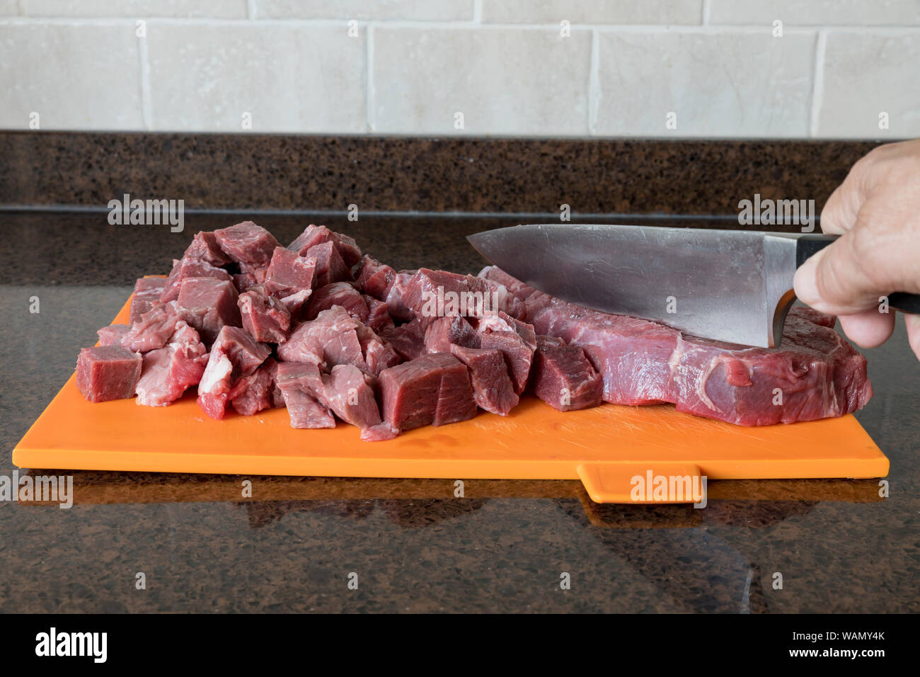 Uomo con taglio di nife un bel pezzo magro di carni bovine è tagliato a pezzi in cucina per preparare un piatto a base di carne Foto Stock