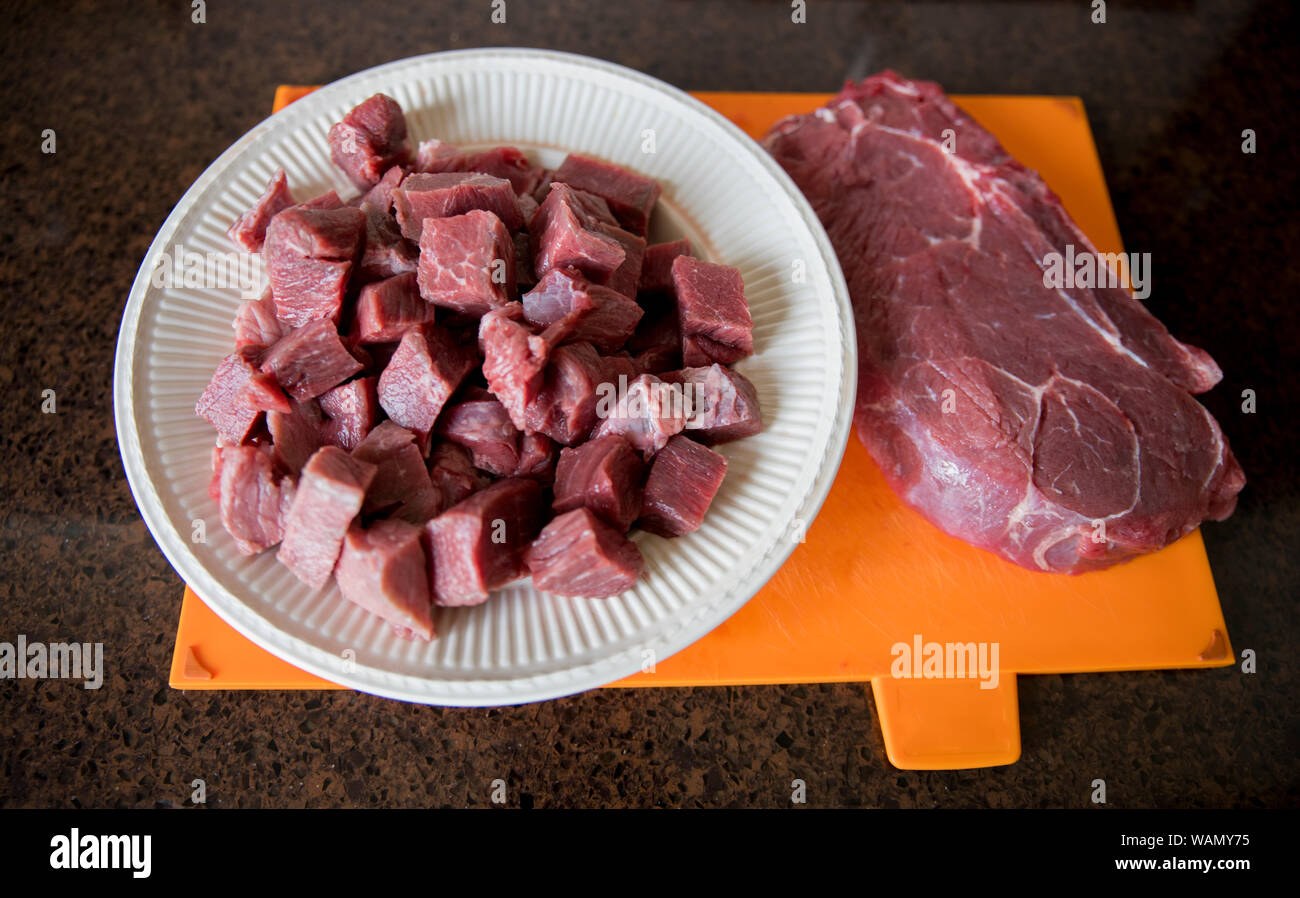 Un bel pezzo magro di carni bovine è tagliato a pezzi in cucina per preparare un piatto a base di carne Foto Stock