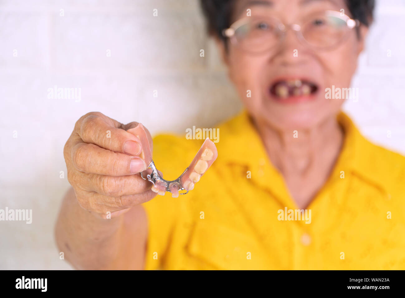 Asian donna anziana oltre 70 anni azienda dentiere in mano. Protesi per dispositivi protesici costruiti per sostituire i denti mancanti e contribuendo a ch Foto Stock