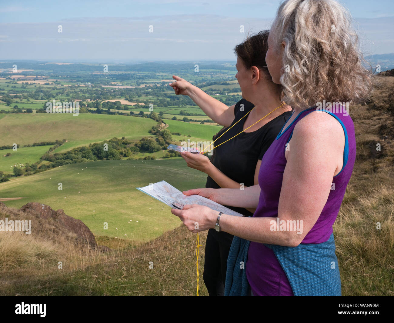 Due donne su un corso di abilità all'aperto che impara la navigazione per mappa e bussola nelle colline di Shropshire, Regno Unito Foto Stock