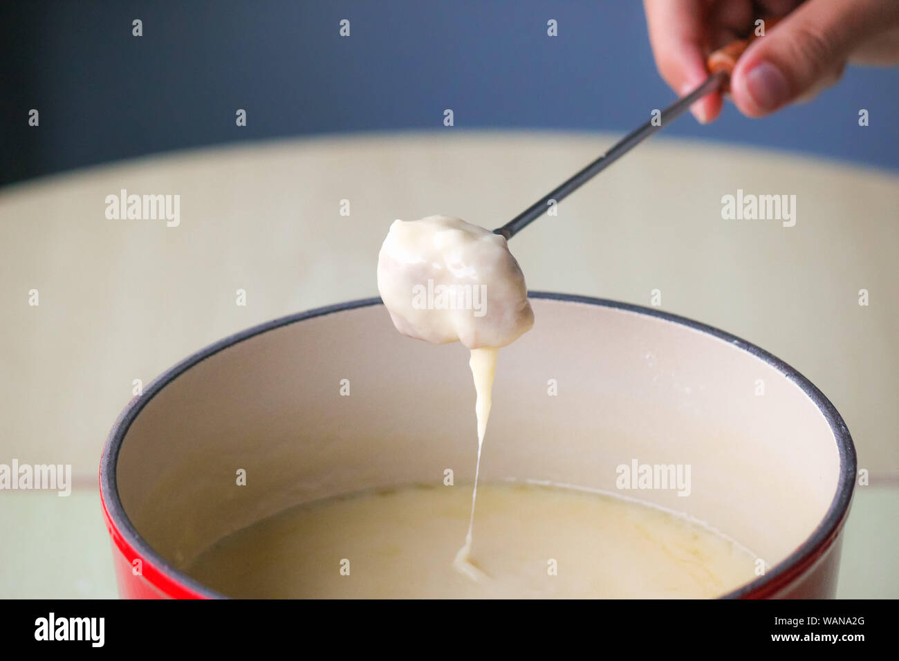 Swiss piatto tradizionale - la fonduta di formaggio. Baguette su una fonduta forcella è essendo immerso nel formaggio fuso. Servita in una pentola comunale riscaldato con una candela o lampada di spirito. Chiudere l'immagine. Foto Stock