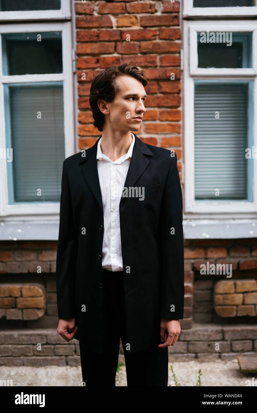 Uomo in un business suit permanente sulla strada nel vicolo Foto Stock