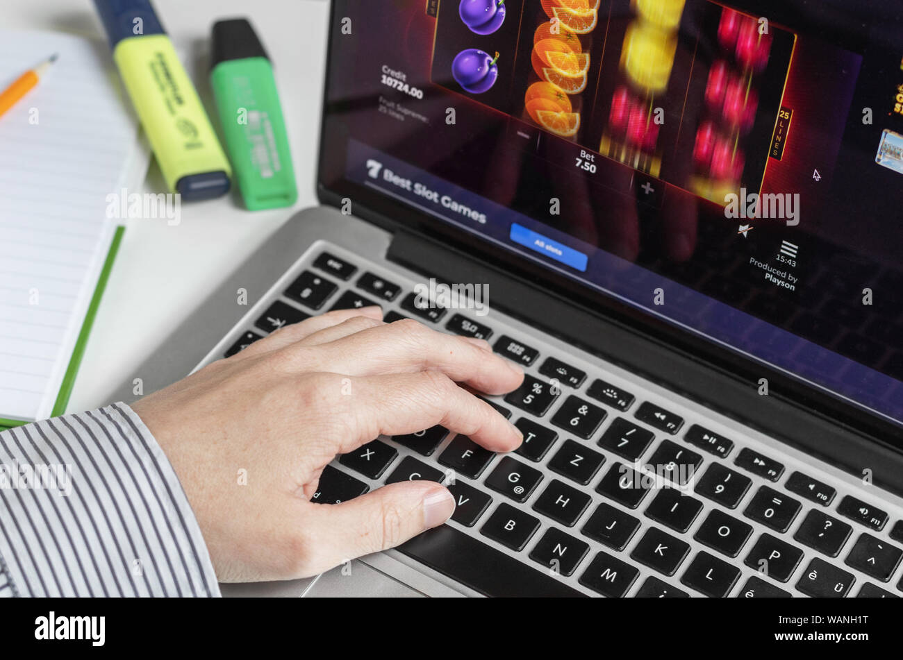 London / UK - 14 agosto 2019 - Il gioco d'azzardo online sul posto di lavoro e la persona alla tastiera di un computer la riproduzione di frutta slot machine Foto Stock