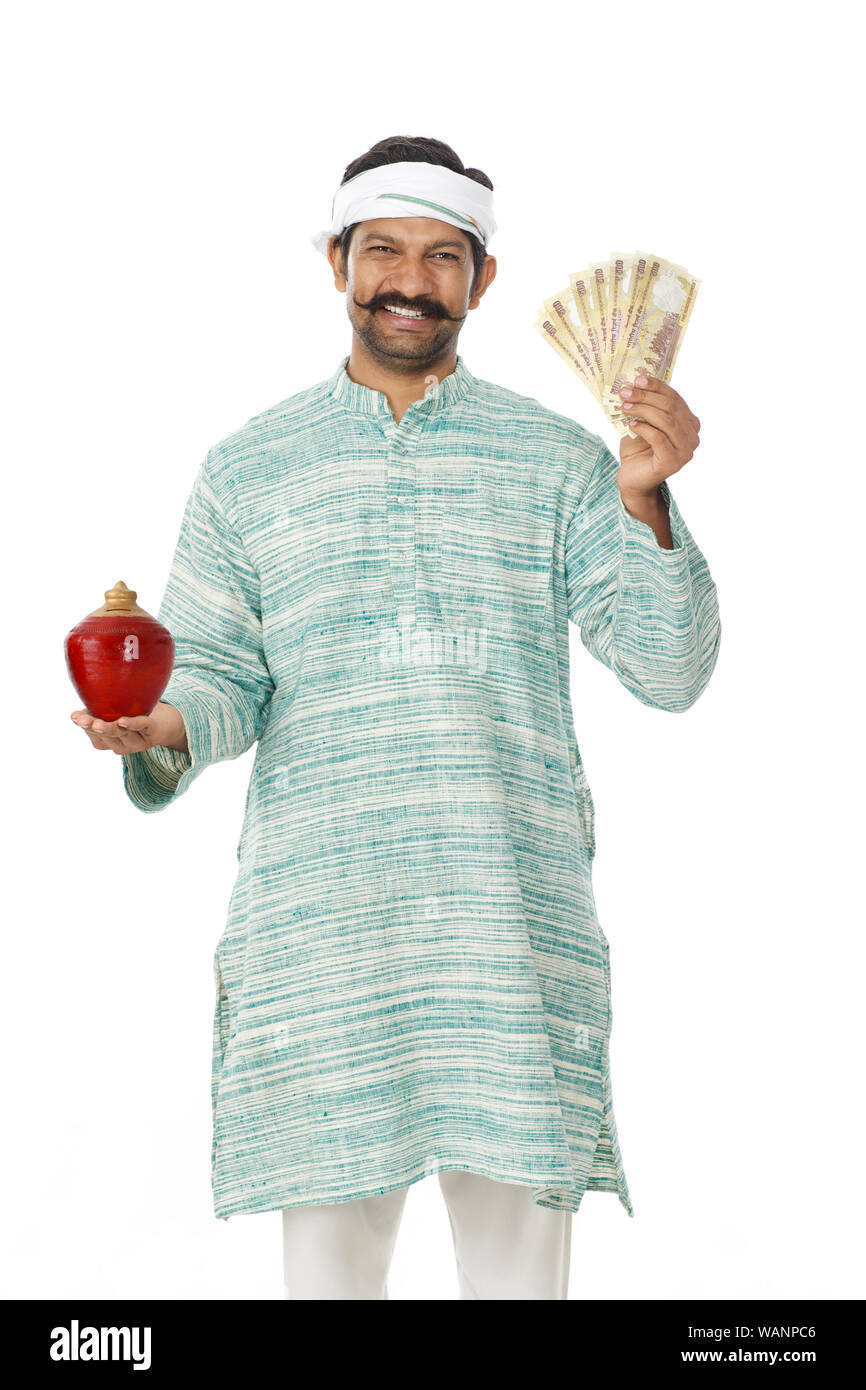 Uomo rurale che detiene cinquecento banconote da rupia e piccgybank Foto Stock