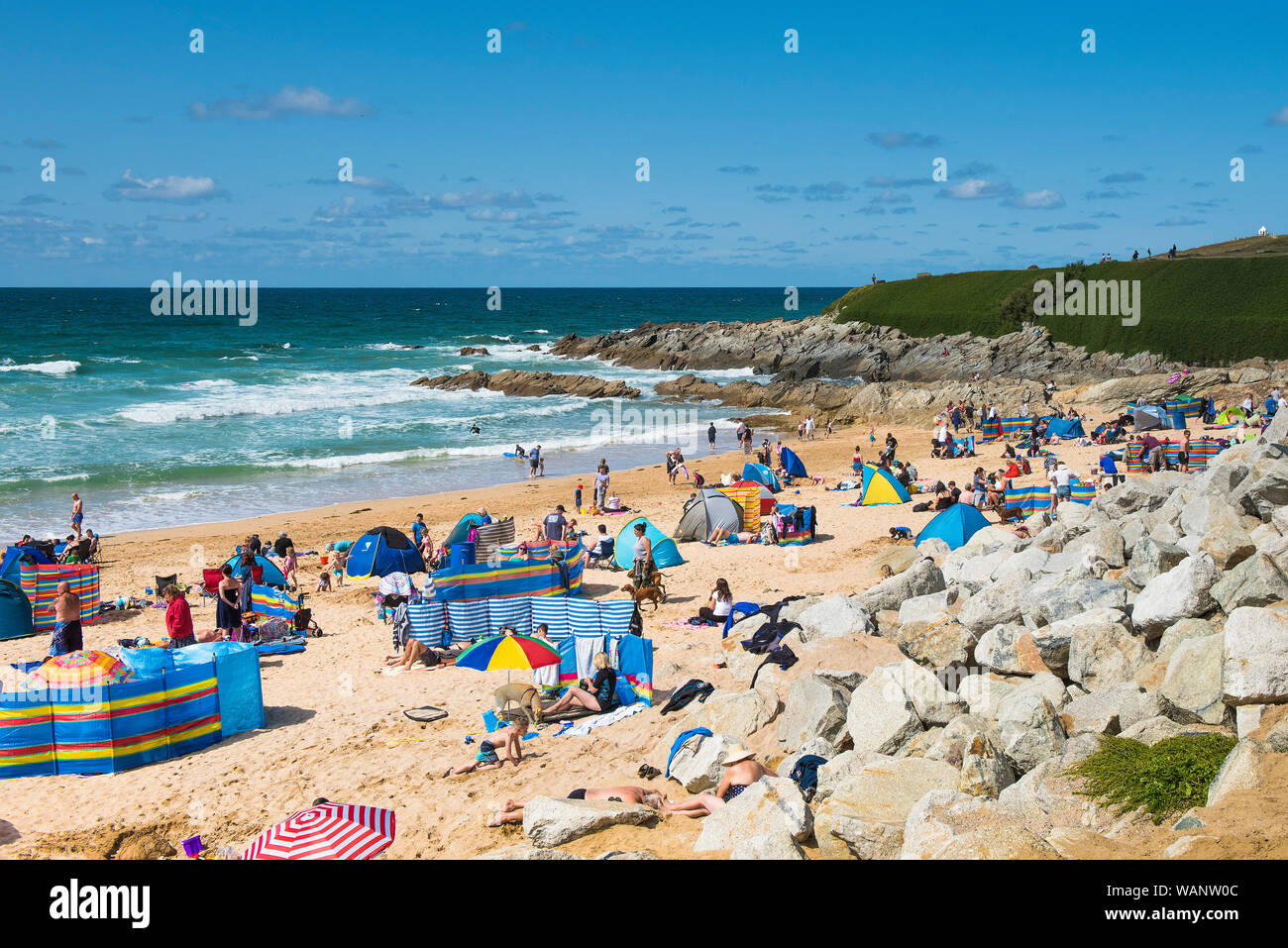 I turisti in vacanza in vacanza su una soleggiata spiaggia Fistral a Newquay in Cornovaglia. Foto Stock