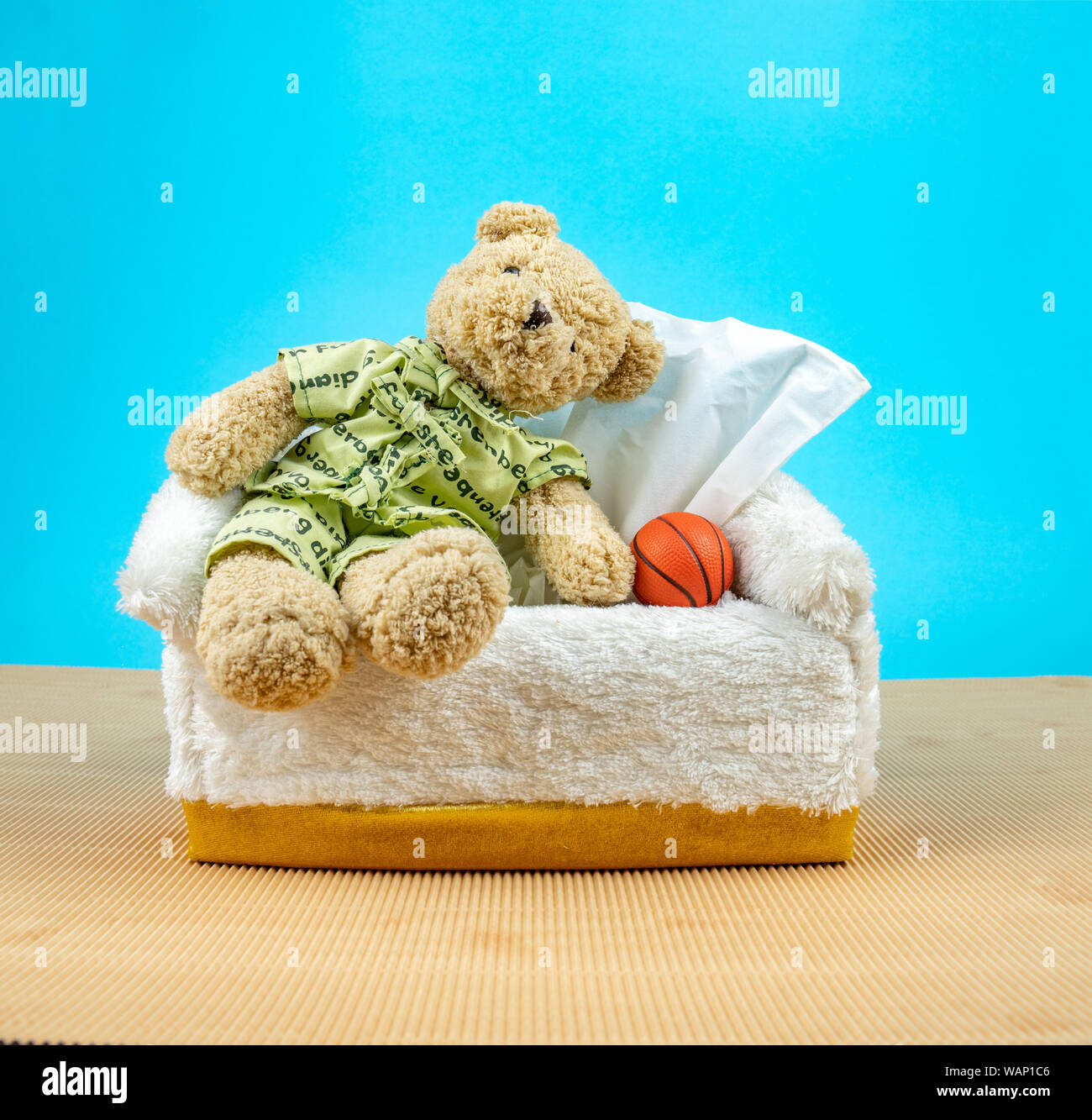 Orsacchiotto di peluche indossare il pigiama e sedersi sulla casella di tessuto con basket accanto Foto Stock