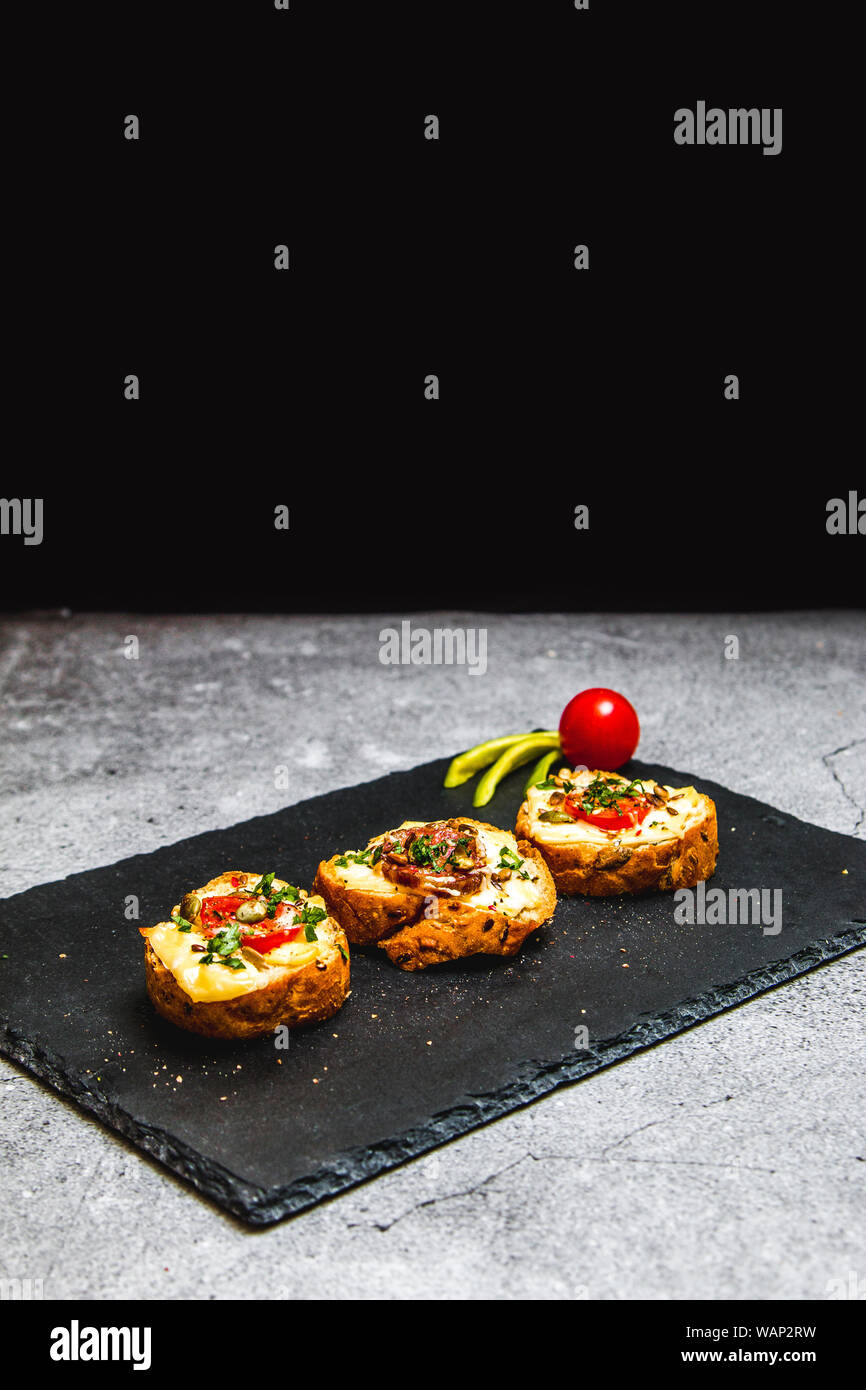 Cotta bruschettes croccante con verdure, formaggi e carni Foto Stock
