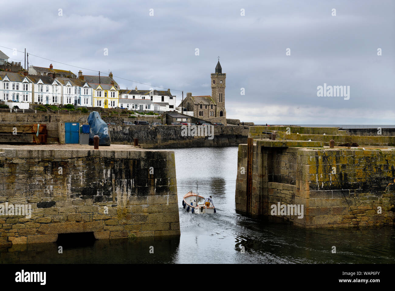 Fisherman lasciando il molo di pietra porto di Porthleven con Bickford smith institute Porthleven storico edificio del Consiglio sull'Oceano Atlantico Cornwall Engla Foto Stock
