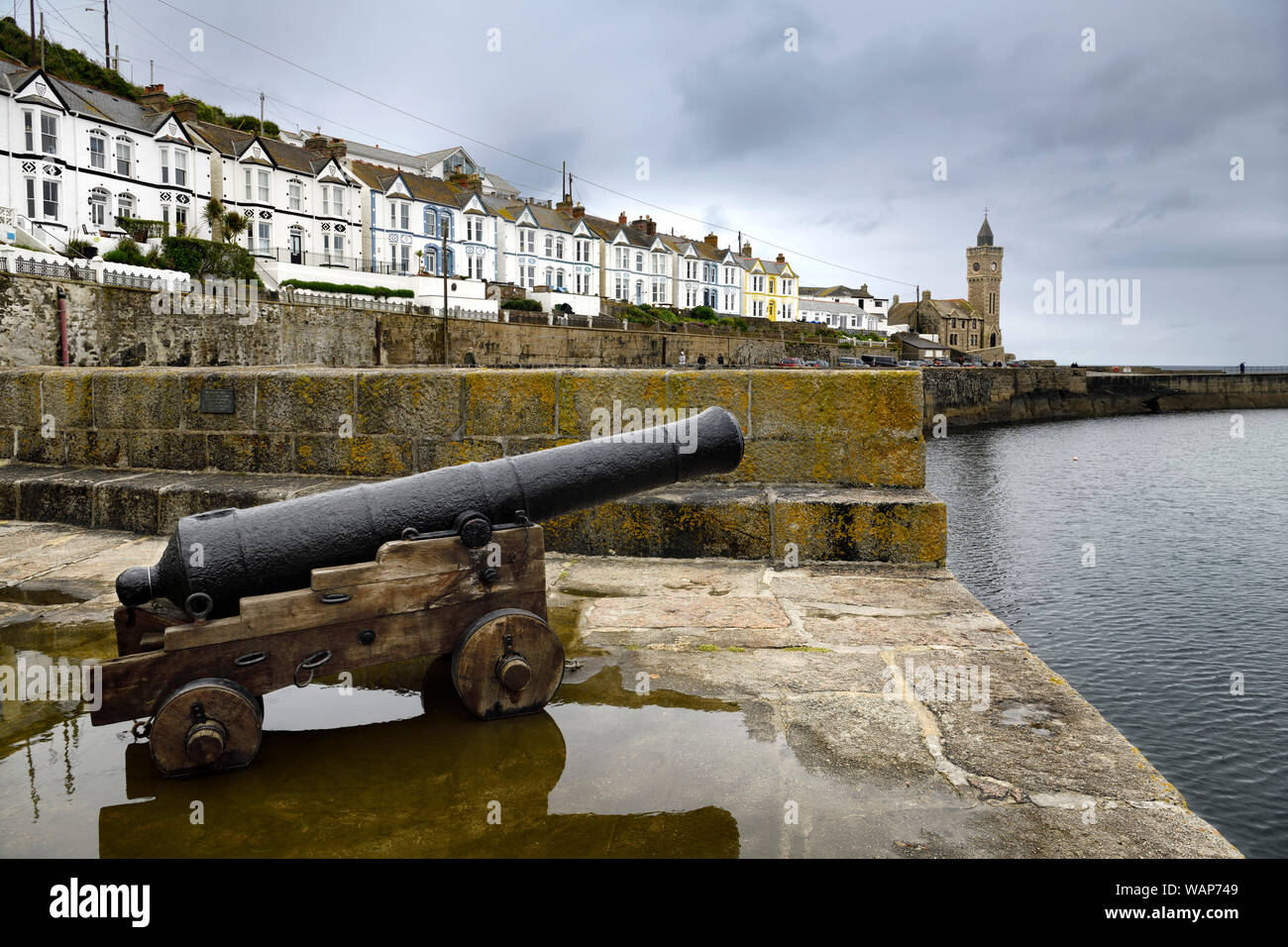 Canon reliquia su pietra del molo del porto di Porthleven con Bickford smith institute Porthleven storico edificio del Consiglio sull'Oceano Atlantico Cornwall Inghilterra Foto Stock