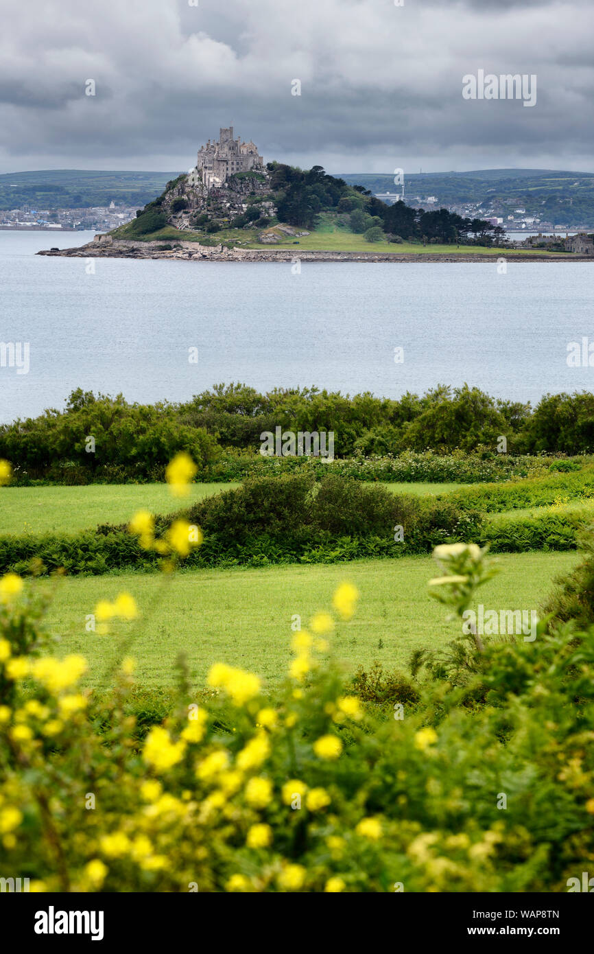 St Michael's Monte Isola di marea sotto cieli nuvolosi in Mounts Bay da campi con giallo Bedstraw in Perranuthnoe Cornwall Inghilterra Foto Stock