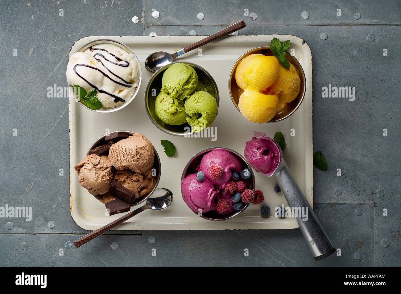 Un assortimento di sapori e colori di gourmet gelato italiano servito sul tavolo in acciaio. Mango, cioccolato, Verde matcha ice cream Foto Stock