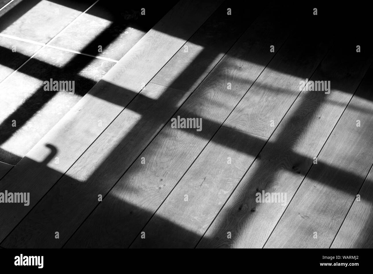 Immagine in bianco e nero dell'ombra di una finestra su tavole di legno all'alba Foto Stock