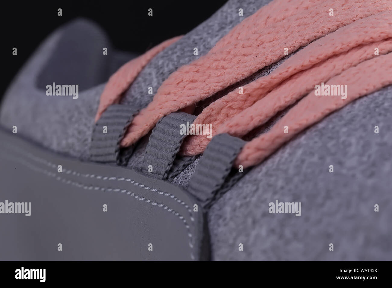 Un frammento di un grigio sneaker con lacci rosa vicino. Texture sneaker Foto Stock