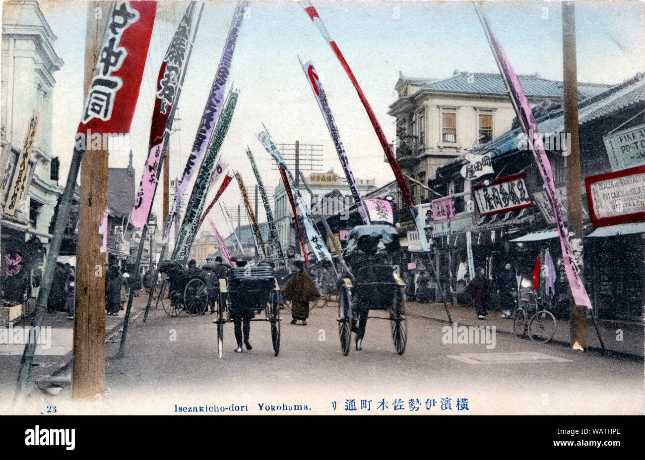 [ 1900 Giappone - Via del Teatro a Yokohama ] - Isezakicho-dori di Yokohama Kanagawa. Rickshaws gara passato colorato di banner pubblicitari. Sulla destra, parte di Hamaya Shoten può essere visto, uno dei numerosi negozi di Yokohama per la vendita di cartoline come questa. Xx secolo cartolina vintage. Foto Stock