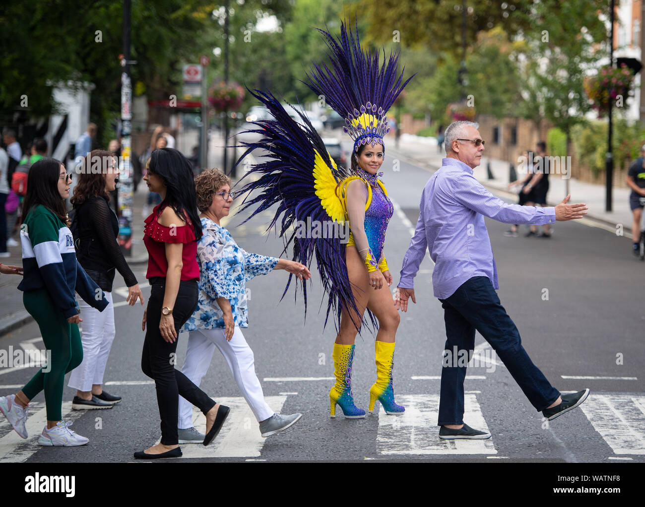 Istruttore di pilates Juliana Campos attraversa la Abbey Road zebra crossing, nel nord di Londra, indossando un brasiliano fatta costume di carnevale, precedendo il carnevale di Notting Hill, che avviene tramite la banca weekend di vacanza. Foto Stock