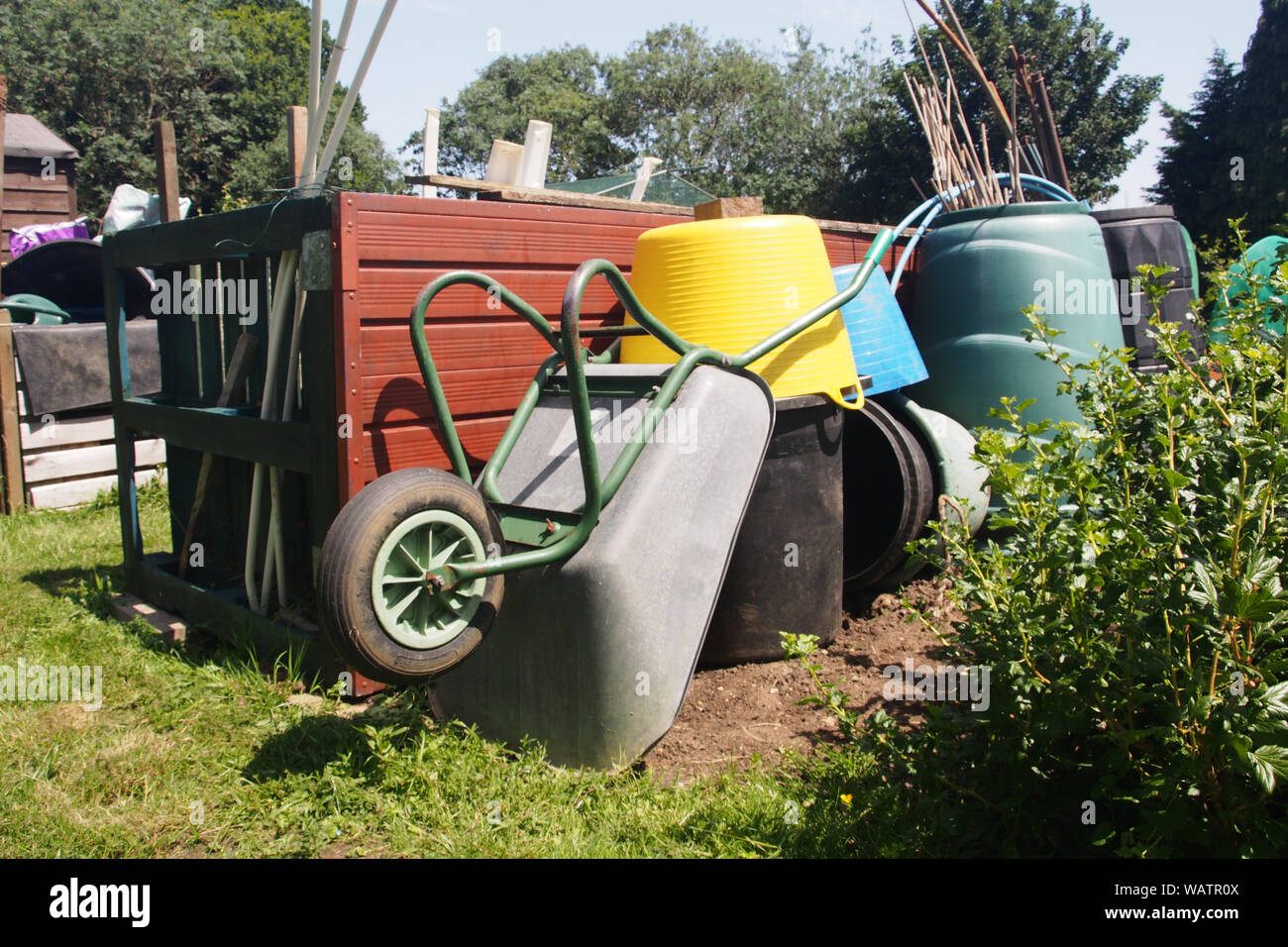 Una ricca collezione di riparto scomparti, benne e contenitori di compost plus una carriola disposti in un heap organizzato Foto Stock